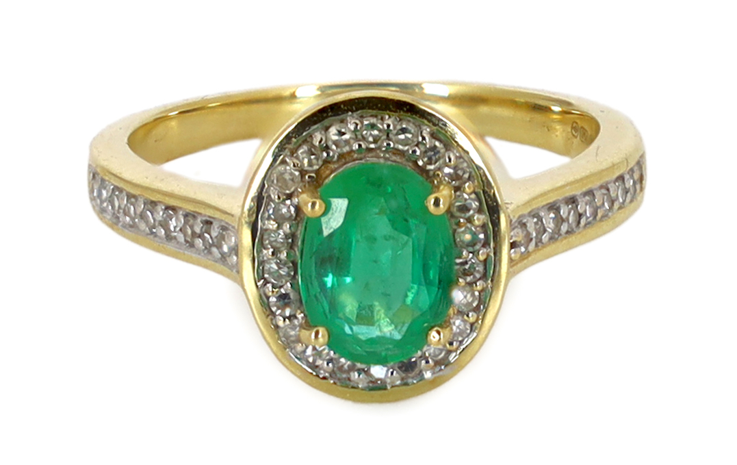 A modern 18ct gold, emerald and diamond set oval cluster ring, with diamond chip set shoulders